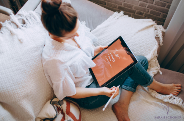 Woman reflecting on career goals while using tablet at home